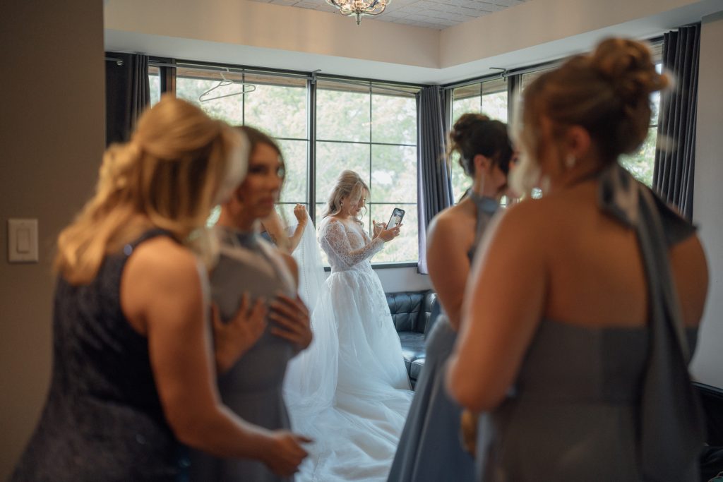 Bride and bridesmaids adjusting her dress near the stone walkway at The Manor